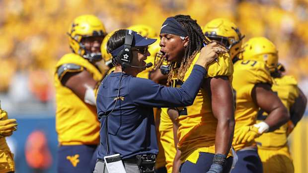 Sep 18, 2021; Morgantown, West Virginia, USA; West Virginia Mountaineers head coach Neal Brown celebrates with defensive lineman Taijh Alston (12) following a turnover during the fourth quarter against the Virginia Tech Hokies at Mountaineer Field at Milan Puskar Stadium.